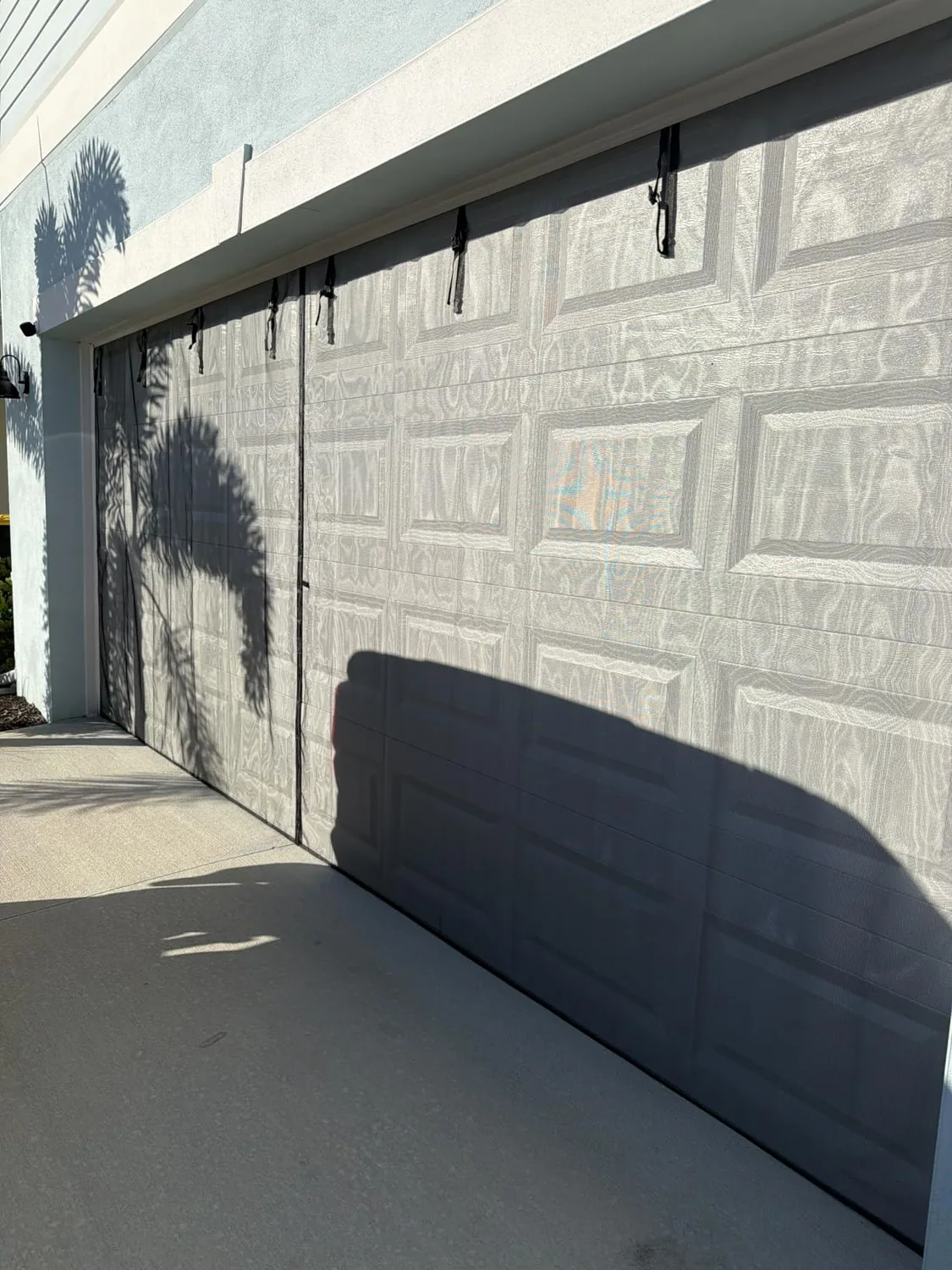 Buyer photo: a black FEGO garage door screen hanging in front of a closed garage door