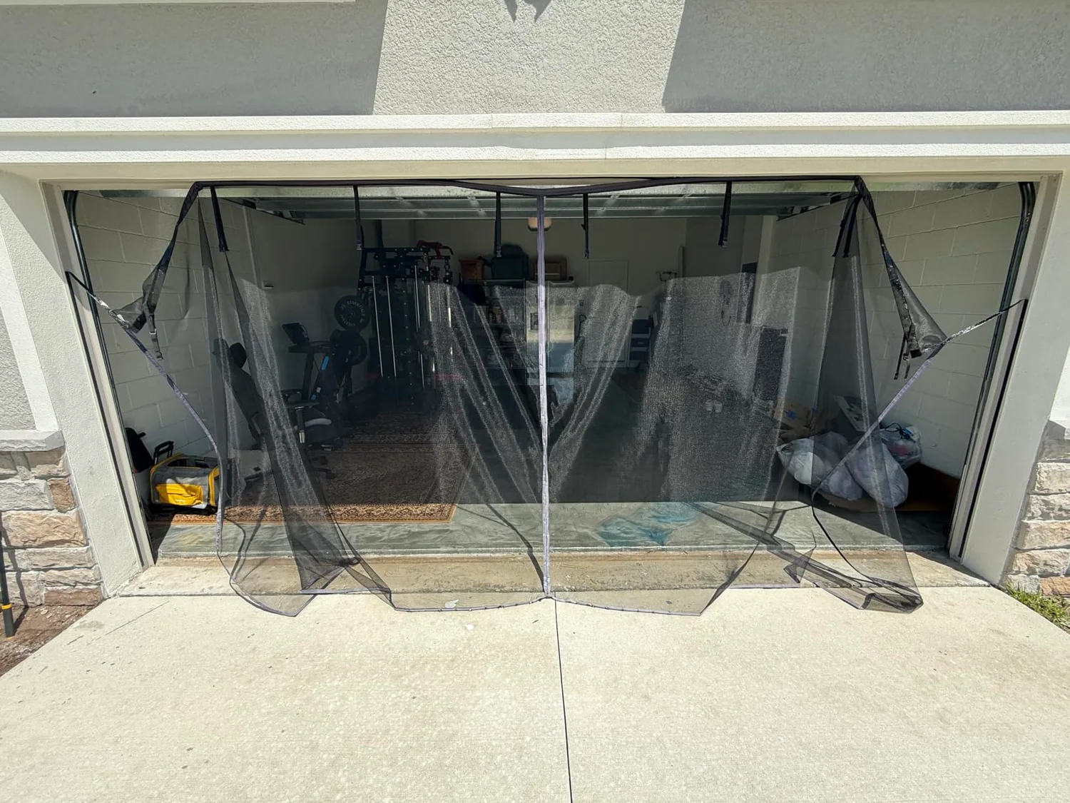Buyer photo: a FEGO garage door screen hanging loose after the adhesive strip let go