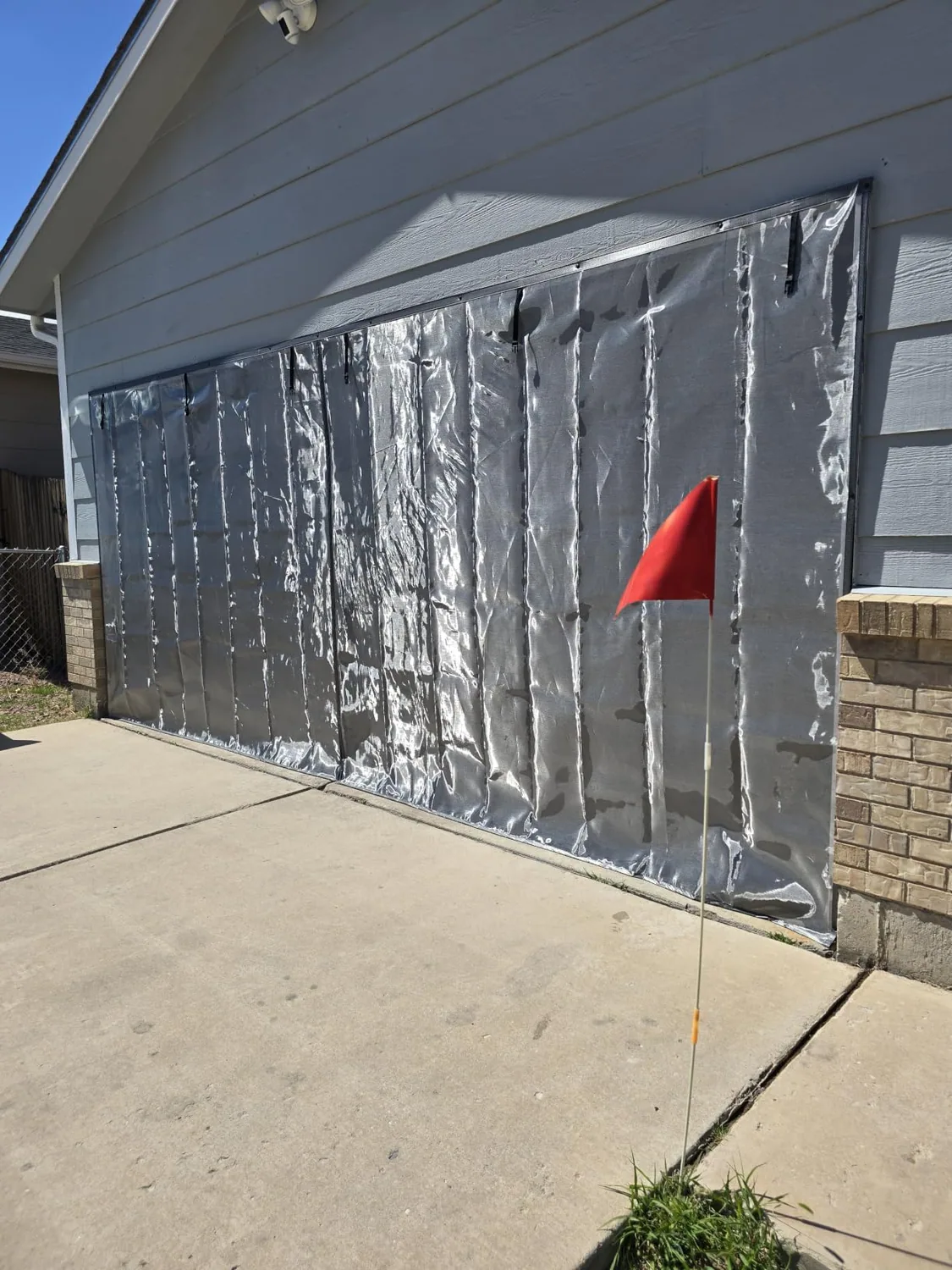 Buyer photo: the silver outer face of a FEGO privacy garage door screen in the sun