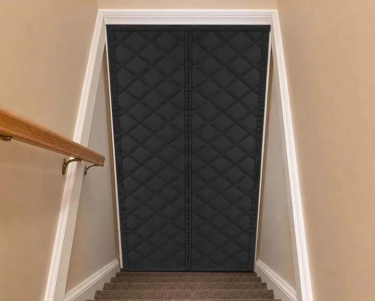 A black FEGO thermal door curtain at the head of a basement stair