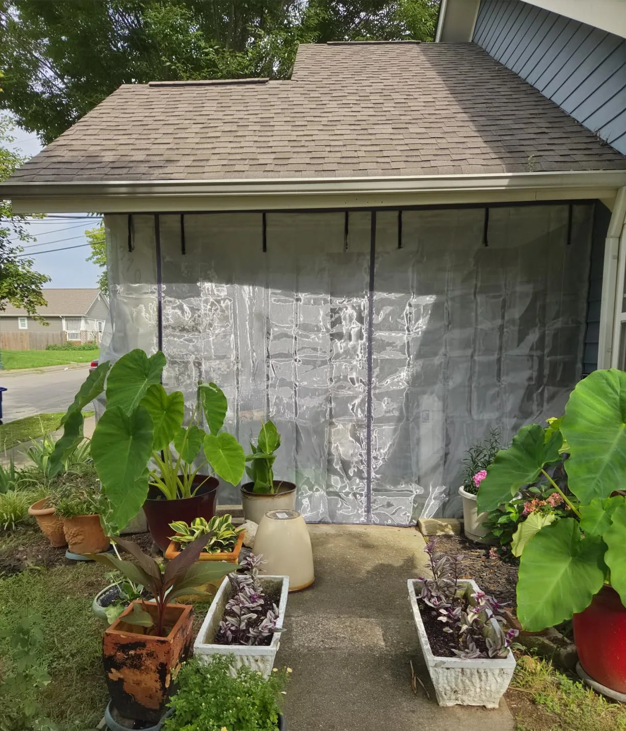 Buyer photo: a FEGO privacy garage door screen closed across a garage behind a row of plants